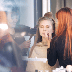 woman applying makeup on model